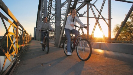 Couple Biking Across Bridge in Downtown Grand Forks All Four Seasons