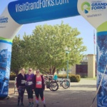 Three Shakespeare Rude Run Participants Posing at the Finish Line Near the Greenway in Grand Forks North Dakota