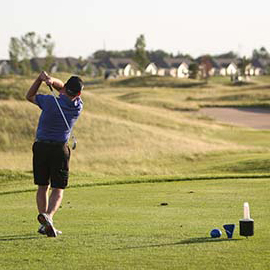Man at golf course in grand Forks hitting a gold ball