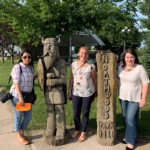 3 women standing outside a Northwood, ND sign