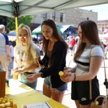 3 girls looking at a honey vendor while shopping at the downtown farmers market in Grand Forks