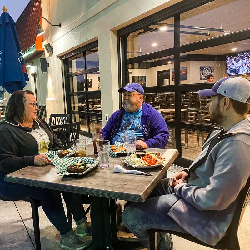3 people enjoying their dinner on a outdoor patio in Grand Forks