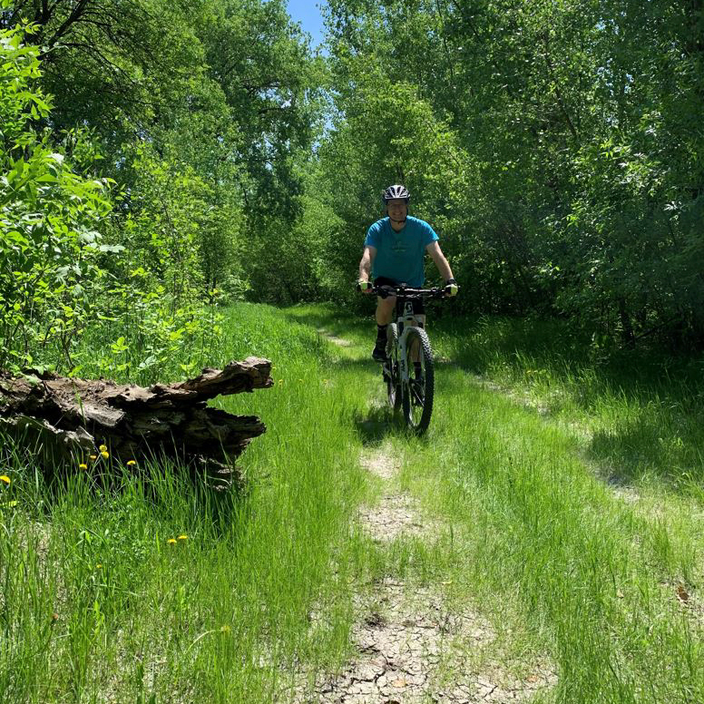 Man bikes on Grand Forks Greenway on summer day