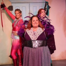 three women in disco costumes pose in Grand Forks theater