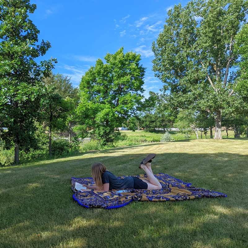 Woman laying in Grand Forks park reading