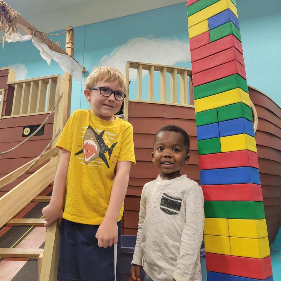 Two young boys stand next to tower of blocks and pirate ship in Grand Forks, North Dakota library