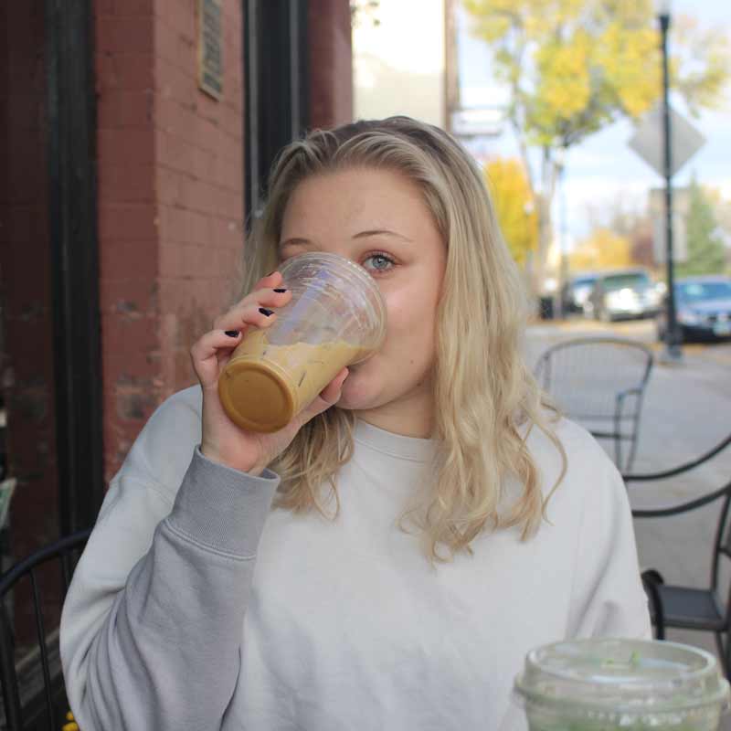 Girl drinking coffee outside coffee shop in Grand Forks, North Dakota.