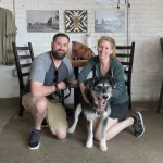 Man and woman pose with dog in Restaurant