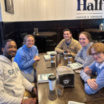 Group of people sit around a table in a coffee shop for a book club meeting in Grand Forks, ND