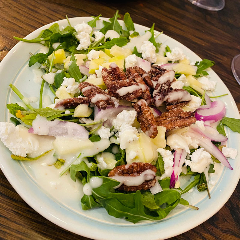 Plate full of salad, red onion, vegetarian protein and dressing in Grand Forks Restaurant