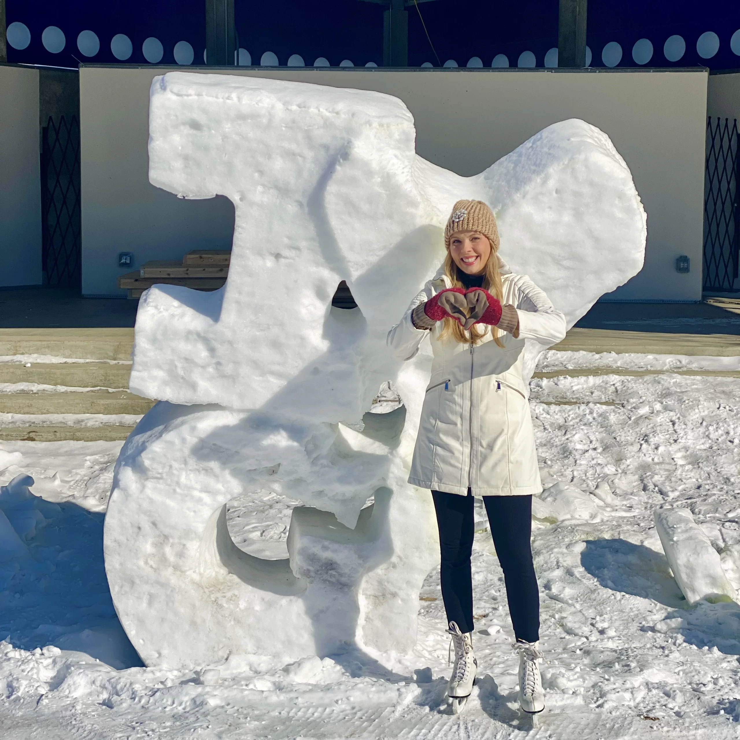 Winter in Grand Forks Cassandra standing in front of ice sculpture that says, ' I love Grand Forks'