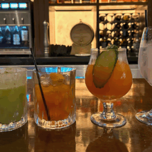 Four drinks on top of a bar counter with the bar in the background.