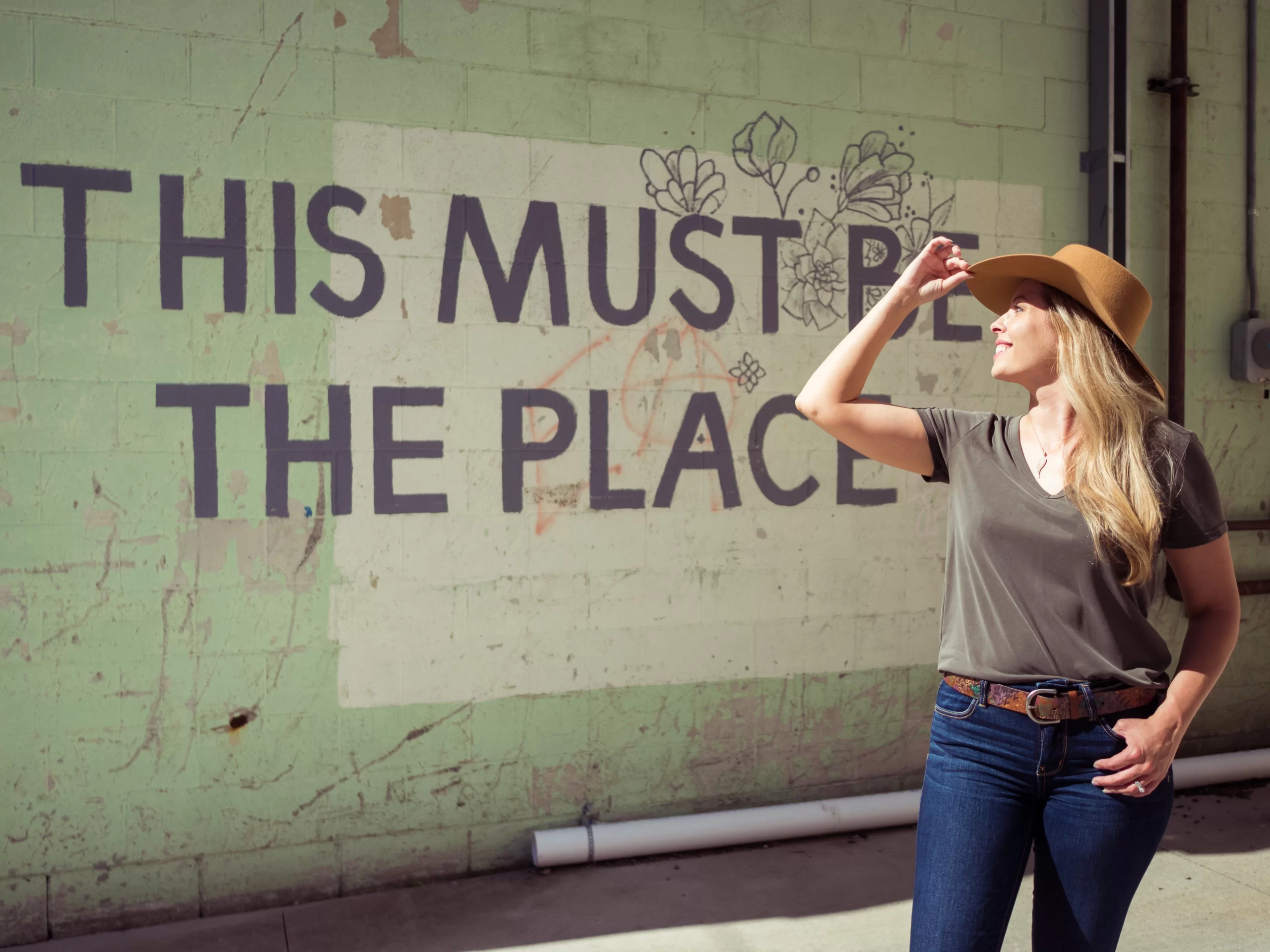 Cassandra in front of a sign that reads 'this must be the place' in downtown Grand Forks.