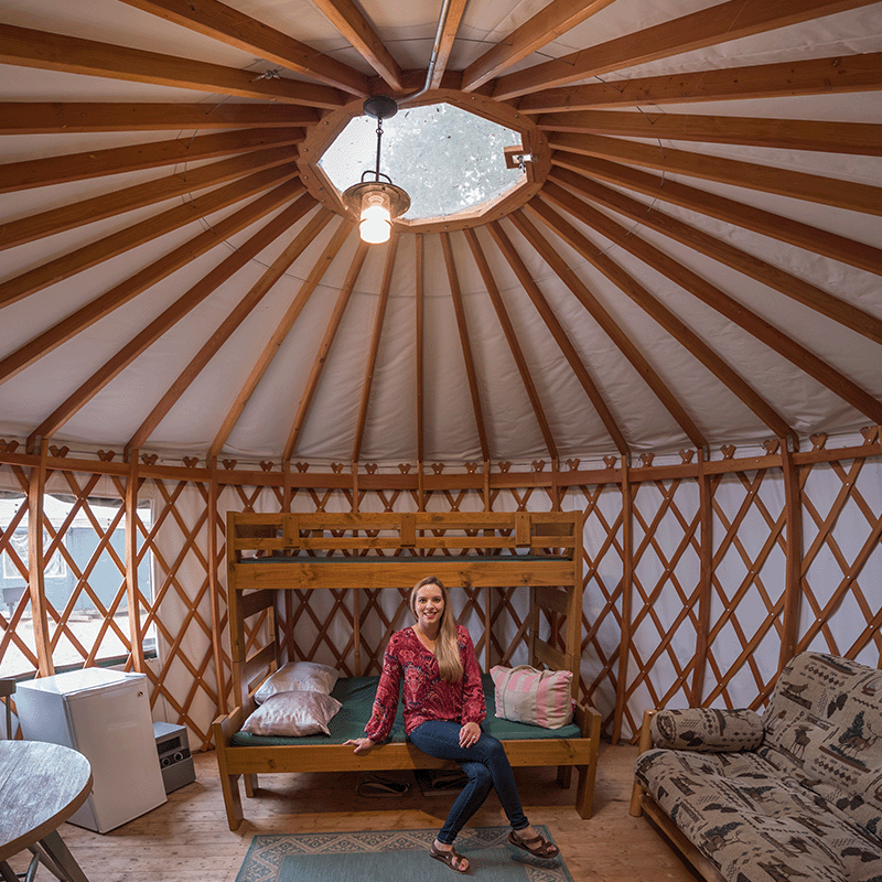 Woman sitting on the bottom of a bunk bed in a yurt along Lake Superior in the Upper Peninsula of Michigan