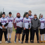 LUG Sports League baseball team posing for a photo on the baseball field with gloves and bats.