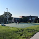 Three people play on a single marked basketball court next to the UND Wellness Center