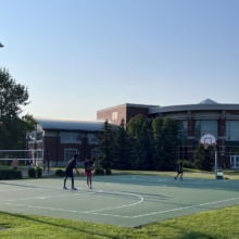 Three people play basketball on the basketball court near the UND Student Wellness Center