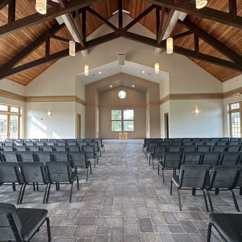 The Hopper Danley altar room with white walls, exposed wood beams, and gray chairs