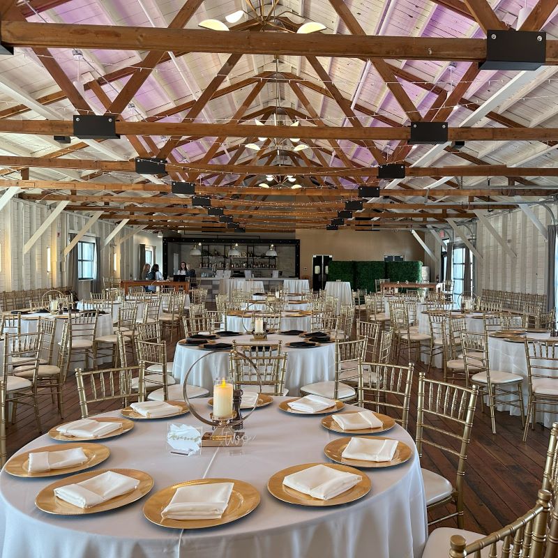The Opal dining room filled with white round tables, gold chairs, and gold dining wear