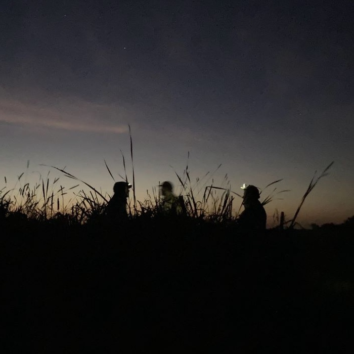 Silhouette of 3 people on a mentored hunt during sunrise.