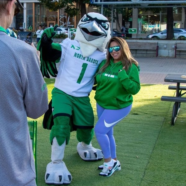 UND Hawk mascot stands posing with a fan in Grand Forks Town Square.