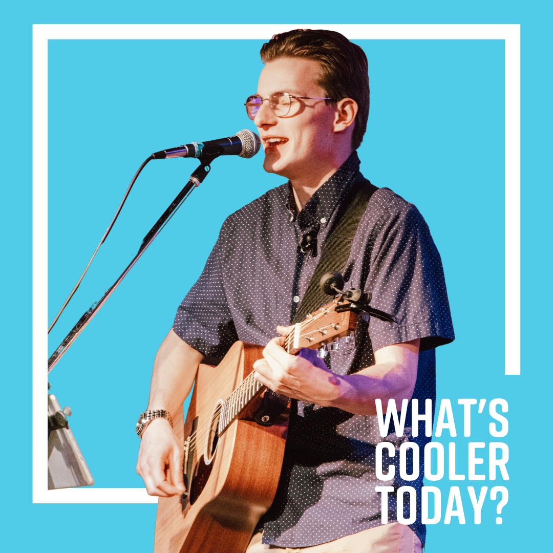 What's Cooler Today writer Andy holds a guitar and sings in a microphone over a blue graphic displaying the WCT emblem.