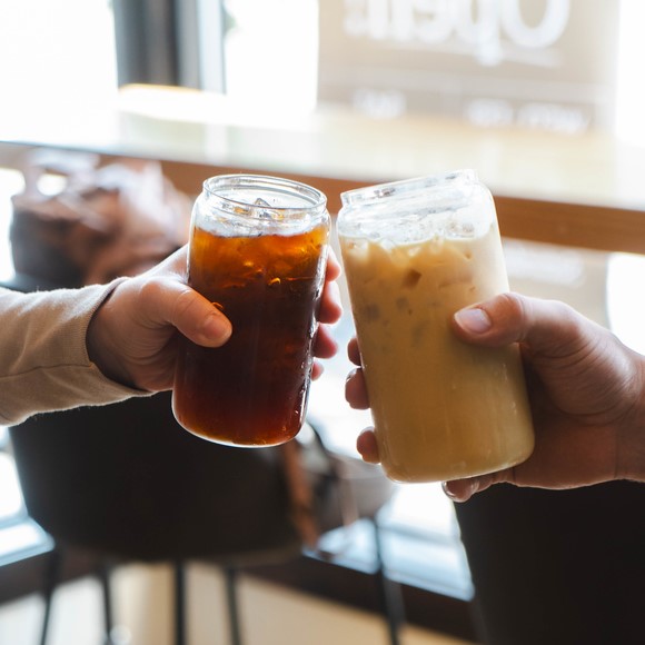 Hands clink two glasses filled with sweet caffeinated goodness