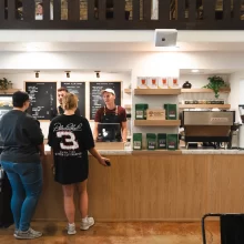 The Ember coffeehouse in Grand Forks. Two people stand at the cash register and two people stand behind it.