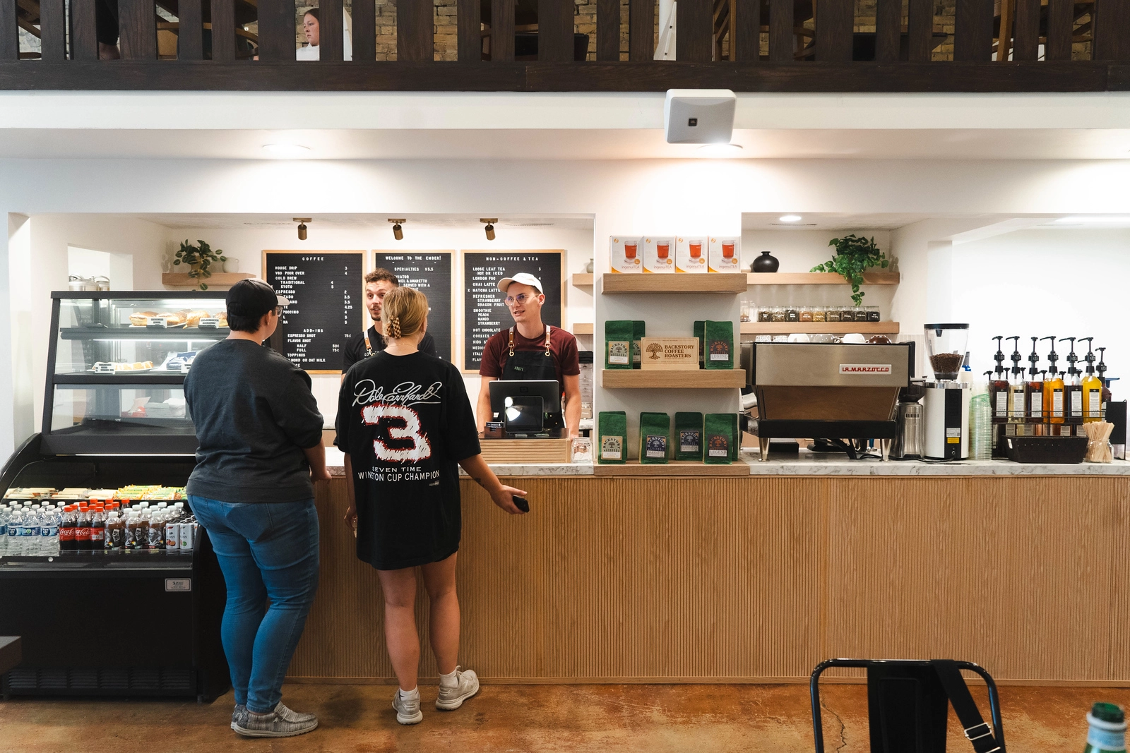 The Ember coffeehouse in Grand Forks. Two people stand at the cash register and two people stand behind it.