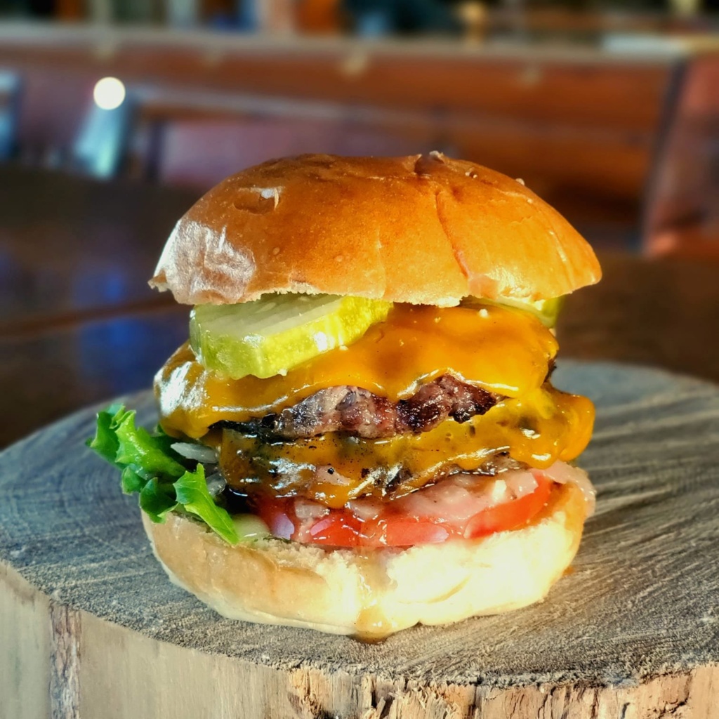 A tall burger sitting on a wooden slab