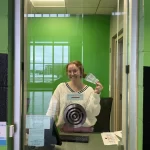 Woman stands behind the box office at the Alerus Center in Grand Forks holding two tickets.