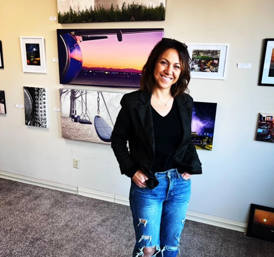 Woman stands in front of art work at Art for Vets event in Grand Forks.