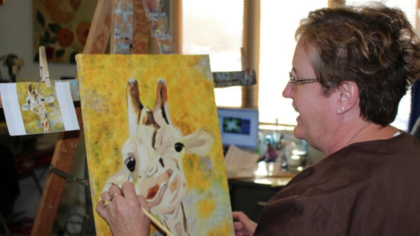 Woman oil painting a yellow picture of a giraffe in Grand Forks.