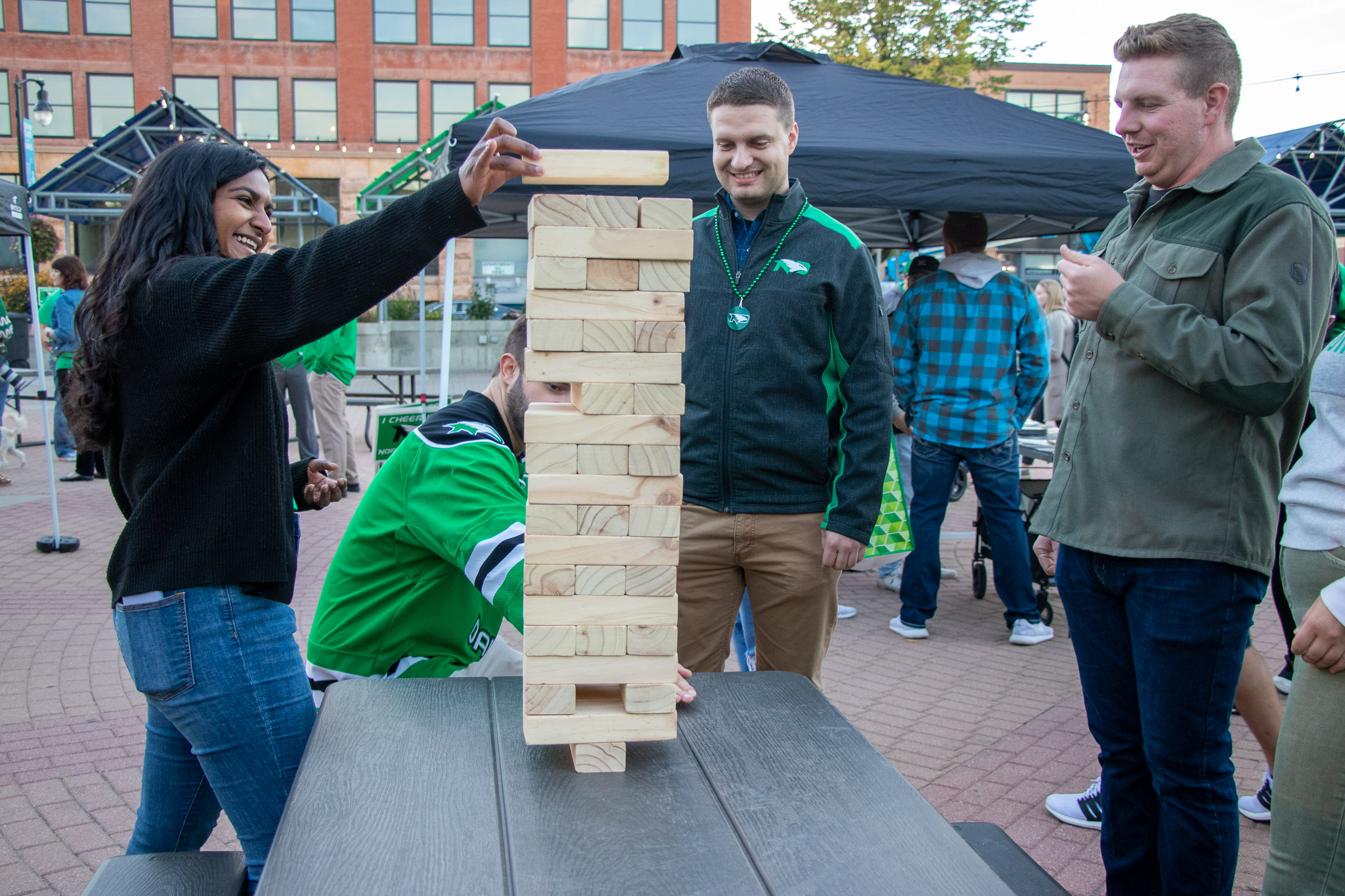 Four people, including WCT writer Paul, gather around a picnic table in Grand Forks Town Square to play an oversized game of Jenga.