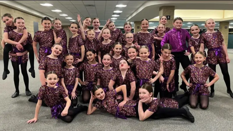 A Grand Forks Dance Team poses for a picture with vibrant purple costumes on.