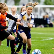 Girls fighting over the soccer ball on the field in Grand Forks.