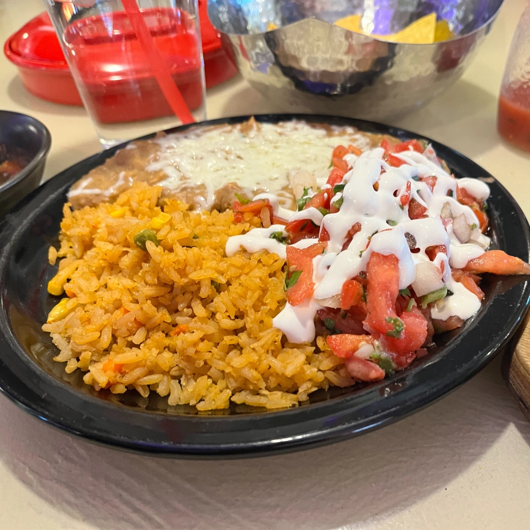 Black plate with rice, beans, tomato, and sour cream in Grand Forks.