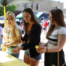 Three girls buying honey at Town Square Farmer's Market in Grand Forks.