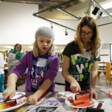 Two young female students focus on an art project involving paint and rollers