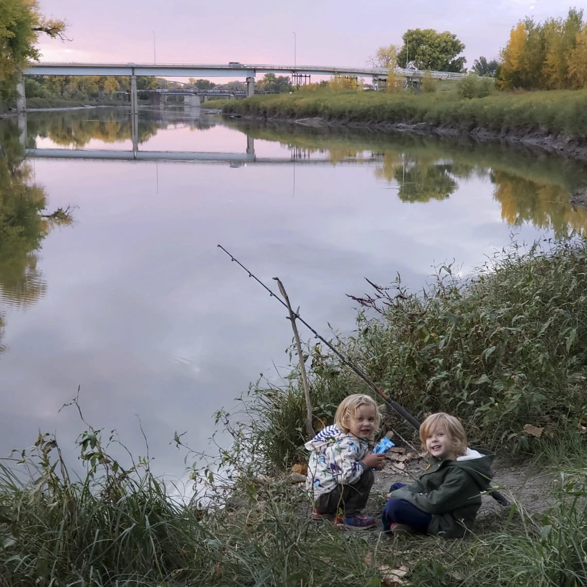 Jude and Avery Anderson fishing on the banks of the Red River at sunset.