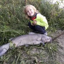 Avery Anderson posing with a Channel Catfish he helped catch off the riverbank near his house. Fish Species: Channel Catfish.
