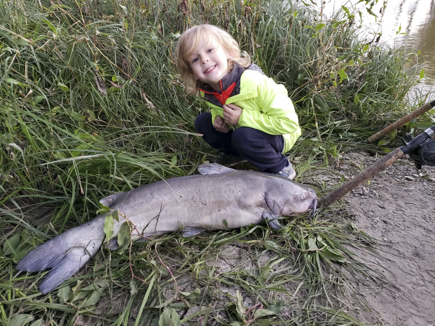 Avery Anderson posing with a Channel Catfish he helped catch off the riverbank near his house. Fish Species: Channel Catfish.