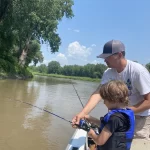 Wade Anderson instructs Jude Anderson on how to catch a fish on the Red River.