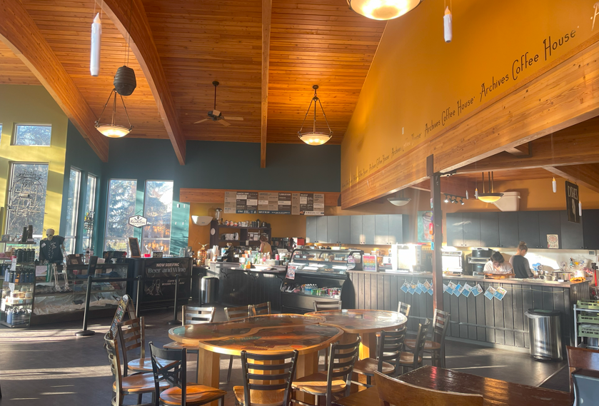 A view of the inside of Archives, showcasing tables, the counter, a bakery display case, and tons of natural lighting.