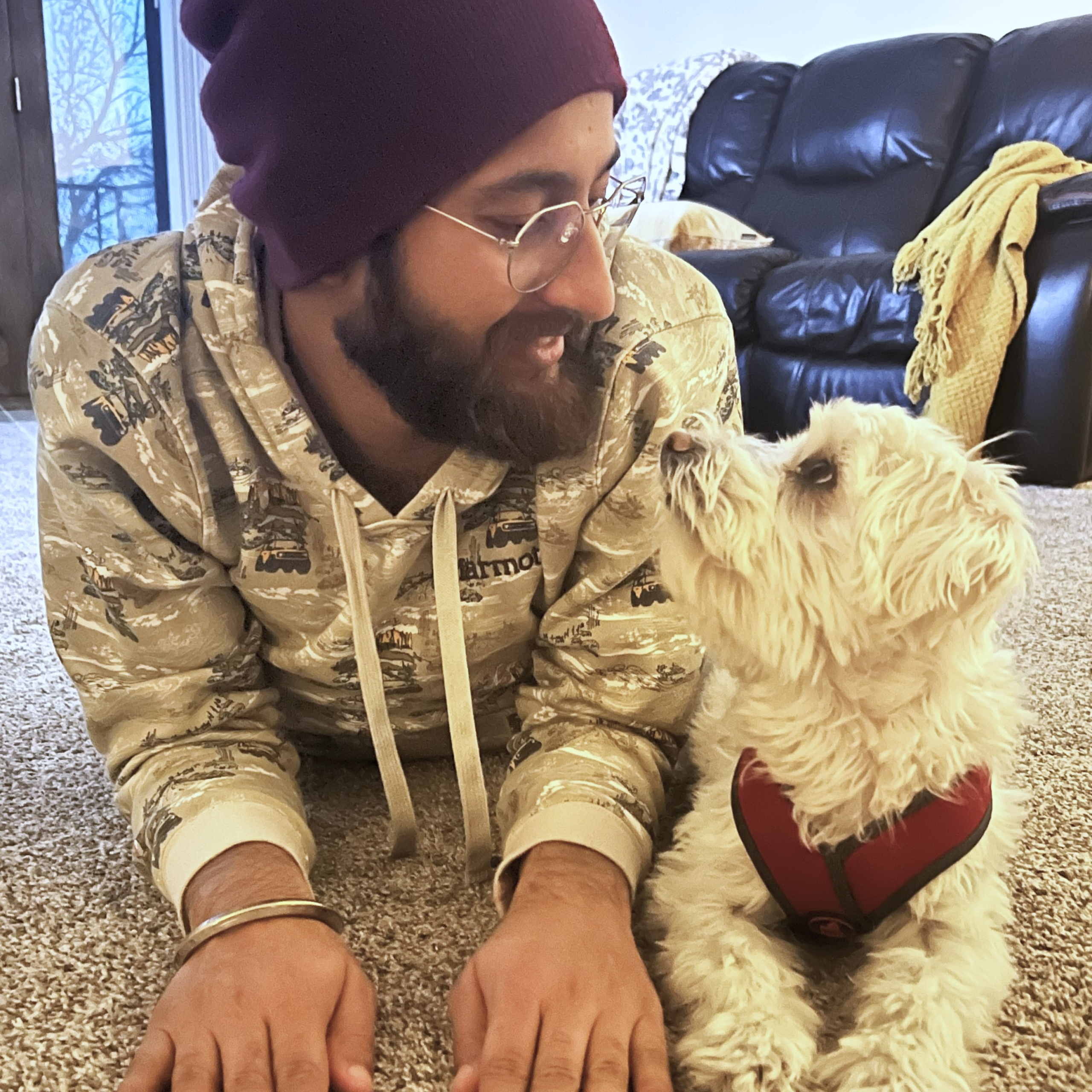 WCT author Benu's partner lies on the floor with their small, white puppy Rio.