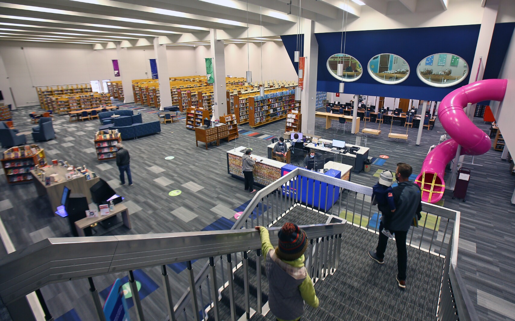 The Interior of the Grand Forks Public Library showcases books, a grand staircase, and an aerial perspective of the second-story childrens's section, complete with a hot pink slide!