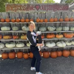 WCT writer Jasmine and her baby in front of pumpkin wall at Nelson's Pumpkin patch