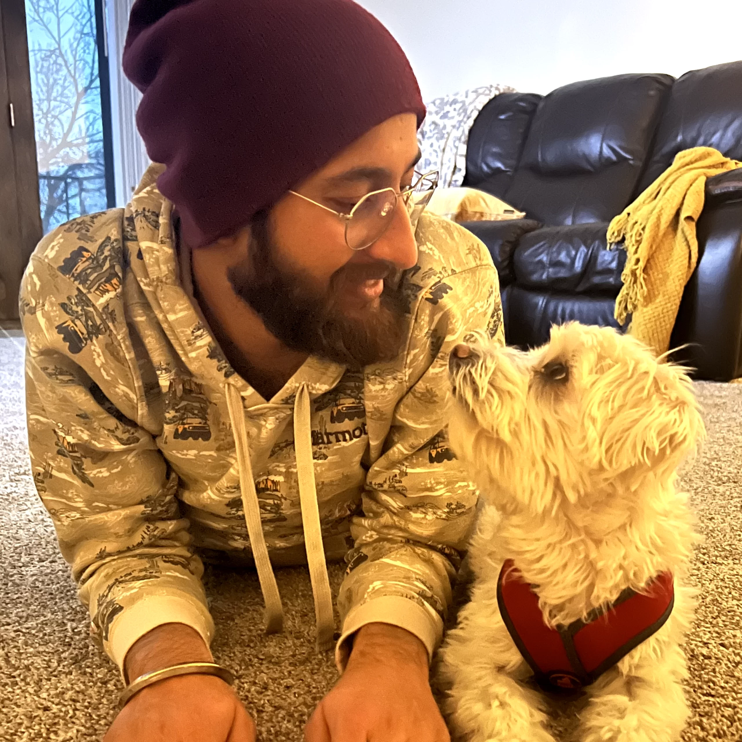 WCT author Benu's partner lies on the floor with their small, white puppy Rio.