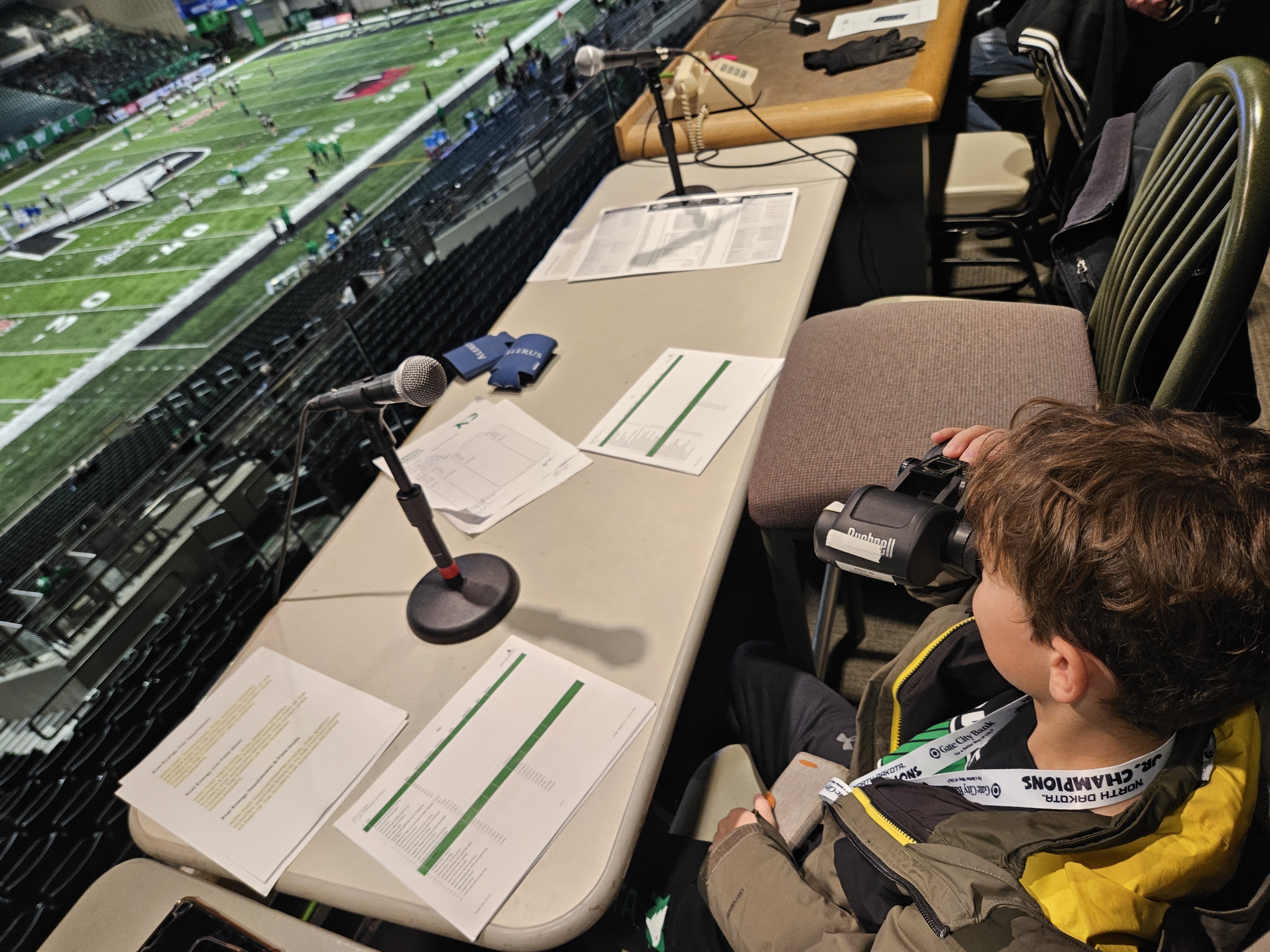 A young boy sits behind the mic at the announcement stand at a UND hockey game