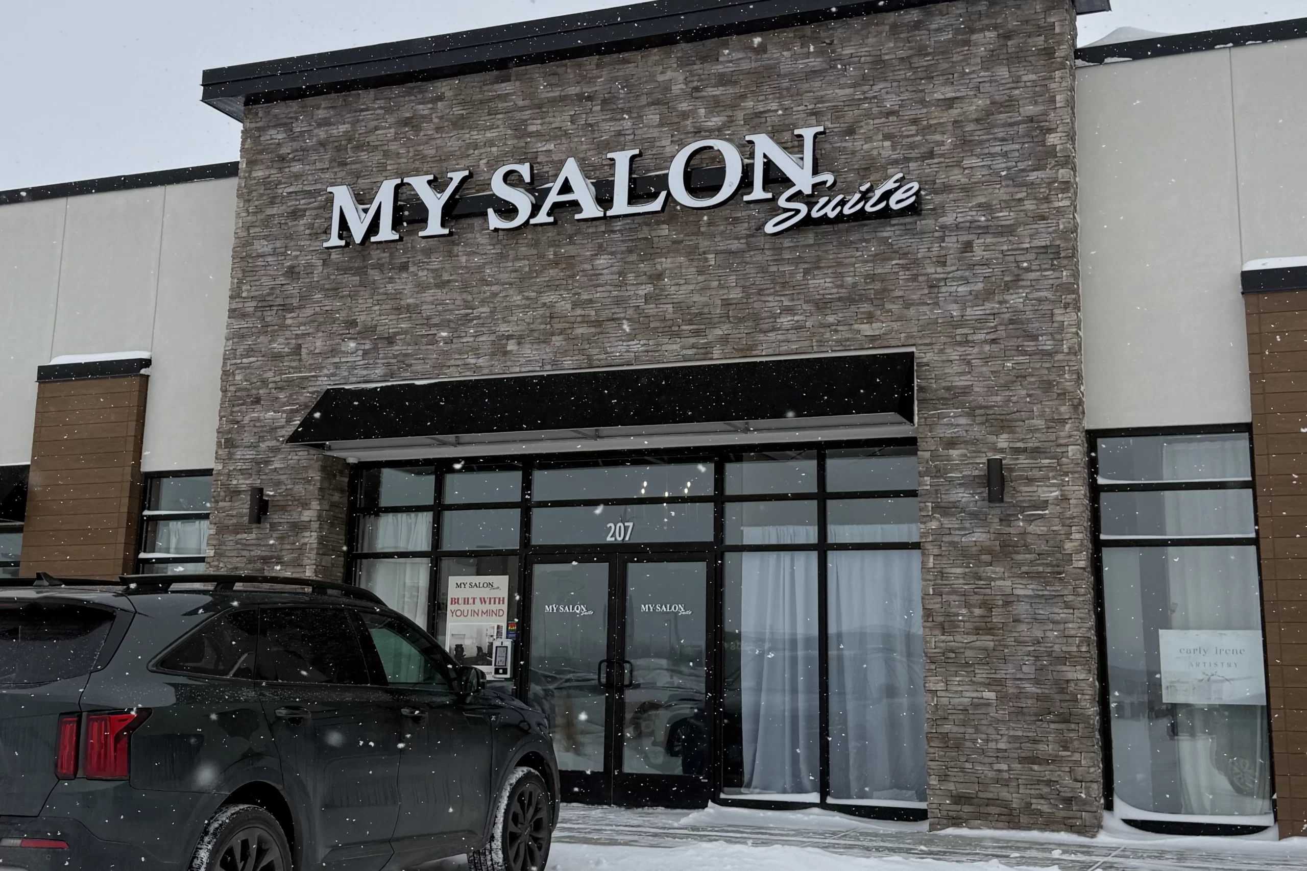 A tan brick exterior of a storefront that reads "My Salon Suite".